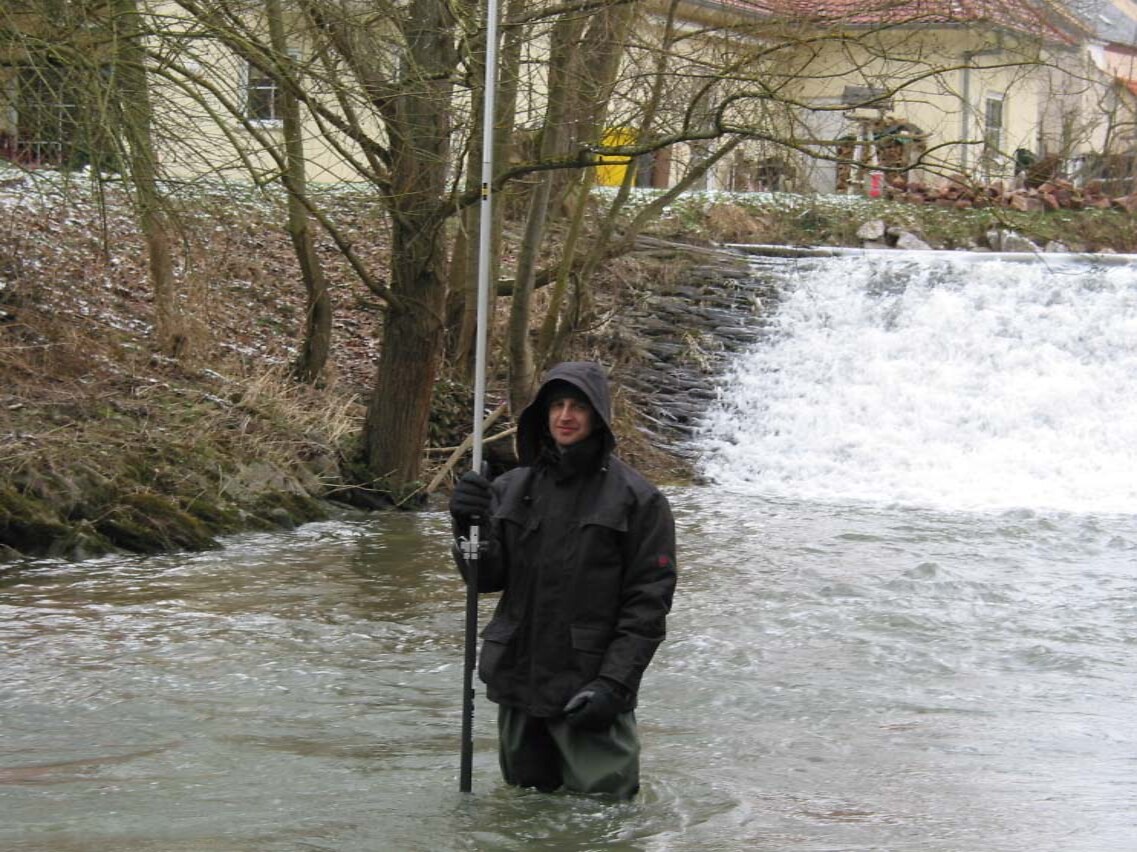 Vermessung mit Messstab im Fluss unterhalb einer Wehranlage